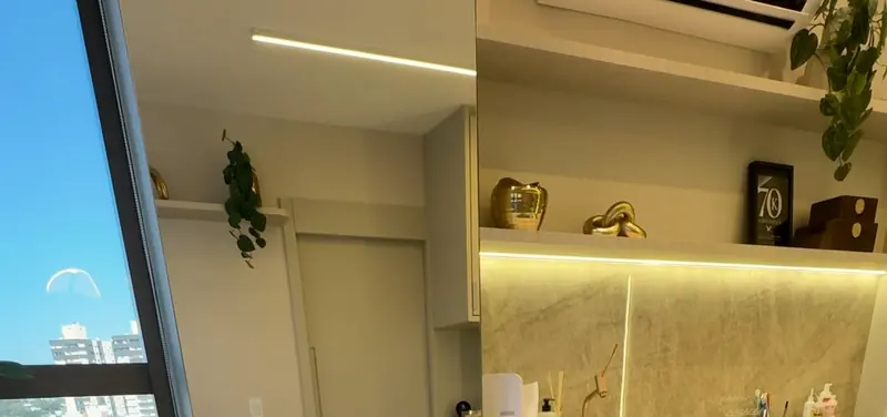 Sala da clínica com bancada de mármore, prateleiras iluminadas e janela para a cidade