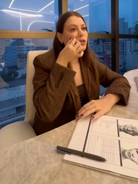 Dra. Paula Budny à mesa da clínica, com as fichas de planejamento facial